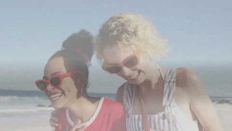 Two women embracing, camera pulling back and starting walking along beach with Video stock 332981818