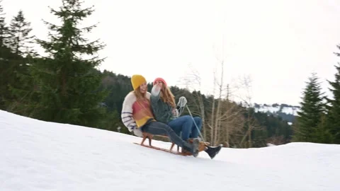 Two women enjoying sledding down a snowy hill in winter Stock Footage 285814145