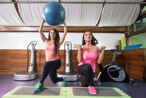 Two women exercise weights stability ball one leg lunge stepper Stock Photos