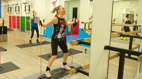 Two women exercising on a balancing platform with resistance bands in a gym.. Stock Footage 328463356