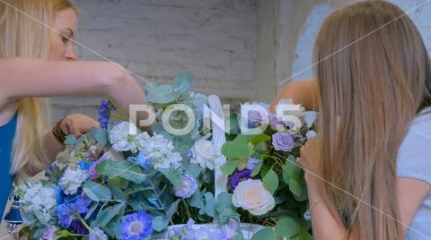 Two women florists making large floral basket with flowers at flower shop Stock Photos