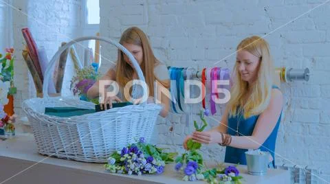 Two women florists making large floral basket with flowers at flower shop Stock Photos