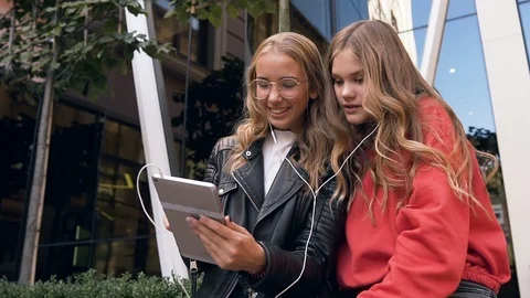Two women friends using digital tablet in outdoors. Smiling girl friends looking Stock Footage 109220307