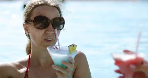 Two women with glasses drink a refreshing cocktail outdoors. Stock Footage 103223605