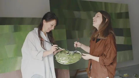 Two women joyfully create abstract art together in a bright studio Stock Footage 322059444