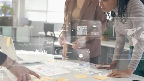 Two women leaning over table moving notes, starting data overlays marking charts Stock Footage 333911204