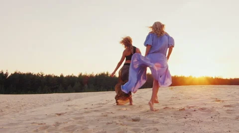 Two women in light dresses run toward the sun. Concept: women's dreams, health Stock Footage 67583395