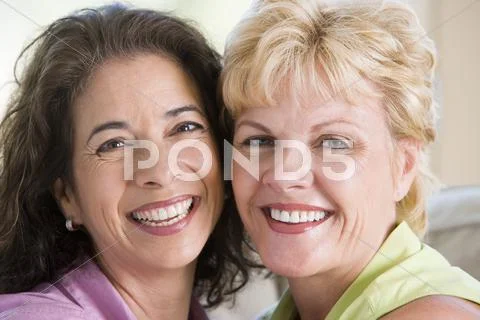 Two women in living room smiling Stock-Fotos