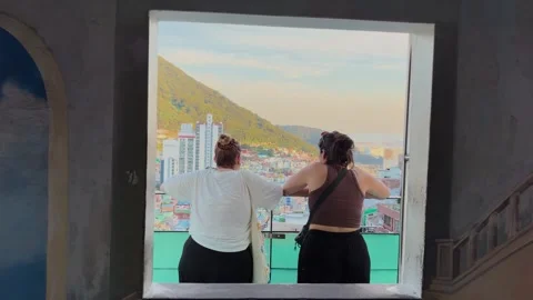 Two women looking through window at gamcheon culture village Stockbeeldmateriaal 343066307