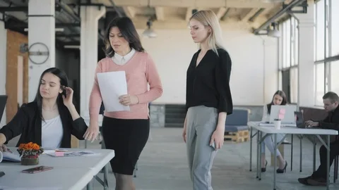 Two women manager walk around the office, communicate, discuss business Stock Footage 124657943