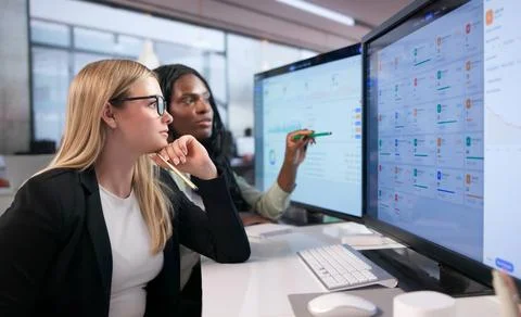 Two Women Managers Discussing Data Analysis While Working On Desktop Computer Stock Photos