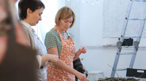 Two women operate with floral elements and talk with each other Stock Footage 65223705
