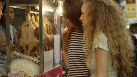 Two women ordering snacks from roadside stall Stock Footage 75292704