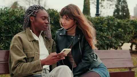 Two Women On A Park Bench Looking At Smartphone Stock Footage 313153103