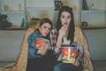 The two women with a popcorn watch a horror movie on the sofa Photo