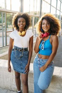 Two women posing while wearing headphones outdoors Stock Photos