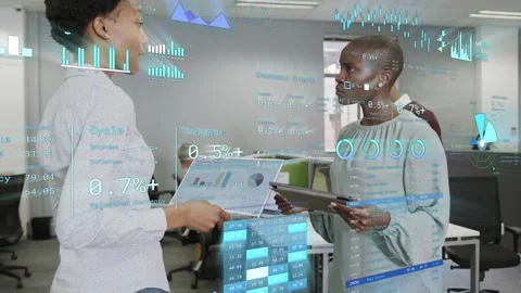 Two women presenting laptop, comparing tablet charts in office, reviewing live Stock Footage 335739603