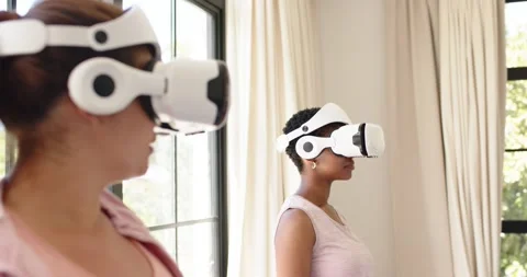 Two women putting on white VR headsets as VR app launches, testing demo by Stock Footage 341852028