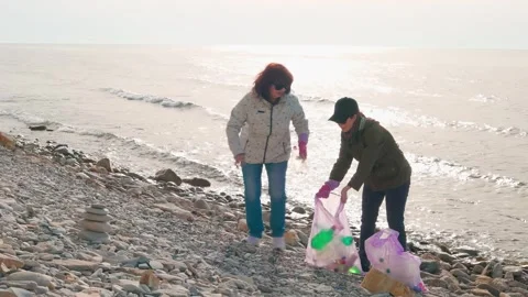 Two women remove garbage from a remote coastline, preventing an ecological 库存影片 305980384