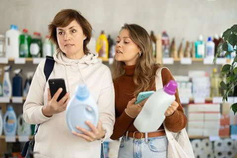 Two women scanning QR-code on detergent in supermarket Stock Photos