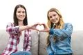 The two women show the heart symbol on the white wall background Photo