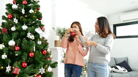 Two Women siblings using hands decorate Christmas tree red ball Video stock 252629196