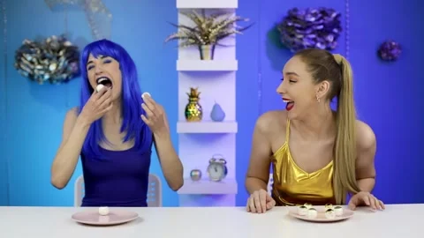 Two women sit at a table at a blue and gold party and grimace Stock Footage 160114742