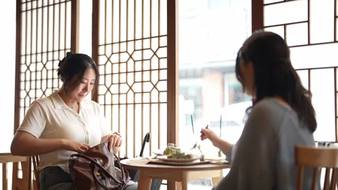 Two women sit at a table in a bright, traditional setting Stock Footage 340934076