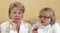 Two women sits on a couch and one woman smokes a cigarette HD Footage