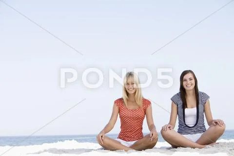 Two women sitting and meditating on a beach Stock Photos