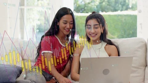 Two women sitting couch, left tapping trackpad, laptop charts animating Stock Footage 333859540