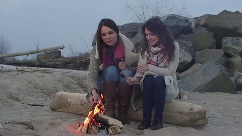 Two women sitting by the fire. BBQ picnic Stockbeeldmateriaal 75806573