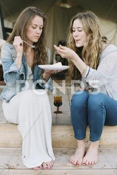 Two Women Sitting Outdoors, Sharing Cake And A Glass Of Wine.