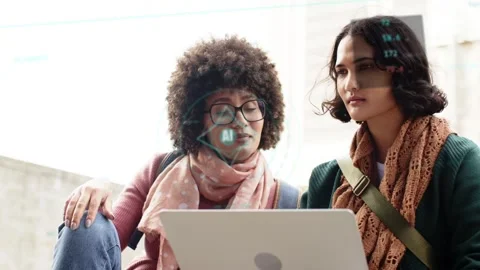 Two women sitting on steps, left woman pointing at laptop, activating AI HUDs Stock Footage 333526215