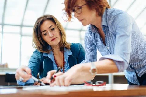 Two women, sitting at table, problem solving Stock Photos