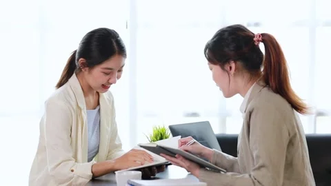 Two women sitting through white papers and talking Stock Footage 217514383