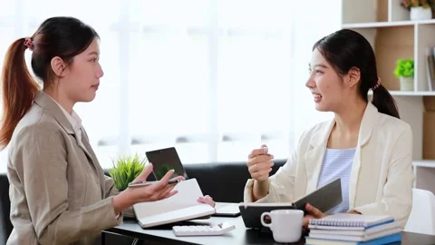 Two women sitting through white papers and talking Stock Footage 217514739