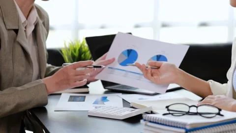 Two women sitting through white papers and talking Stock Footage 217514971