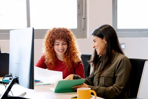 Two women smiling while working together in the office. Foto stock
