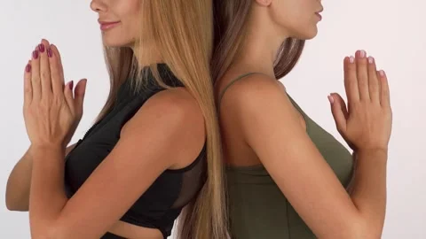 Two women standing back to back with hands in meditation position Video stock 311820015