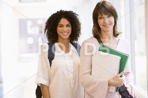 Two women standing in corridor with books (high key) Stock Photos