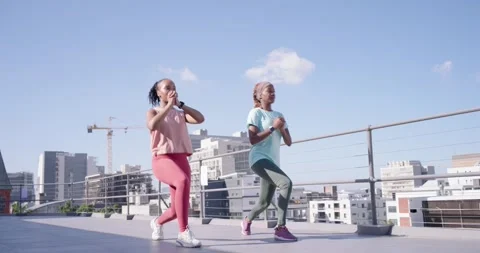 Two women starting workout, walking then lunging in sync on rooftop near Stock Footage 339230184
