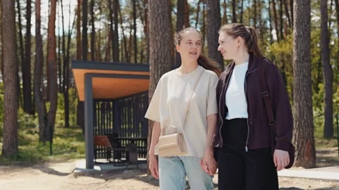 Two women stroll side by side in a forest. They look happy and relaxed as they Stock Footage 336446454