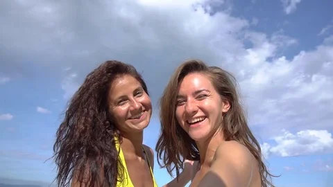 Two women taking selfie using phone on beach smiling and spinning Stock Footage 77855906