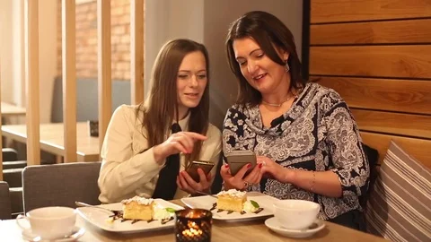 Two women talking and using smartphone sitting in cafe  Stock Footage 72133867