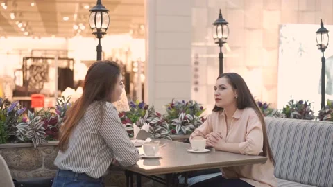 Two women talking in cafe inside a shopping center. the waiter brings an order 库存影片 144598929