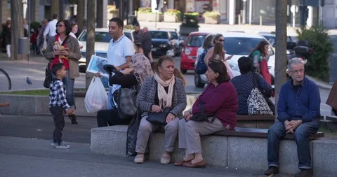 Two women talking sitting on bench, Arab family passing, Germany 4K Stock Footage 96250428