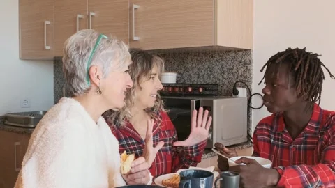 Two women talking with their son while having breakfast in the kitchen at home. Stock Footage 246544815