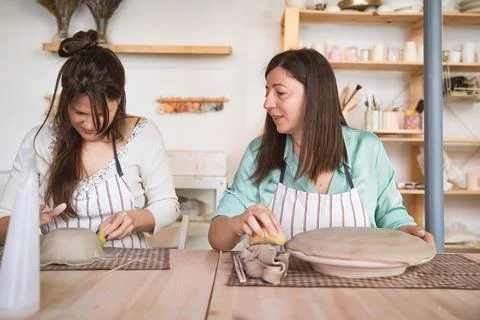 Two women talking while making clay crafts in pottery class. Foto stock