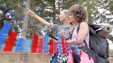 Two women tapping smartphone on forest trail, activating AR navigation graphs Stock Footage 333575232
